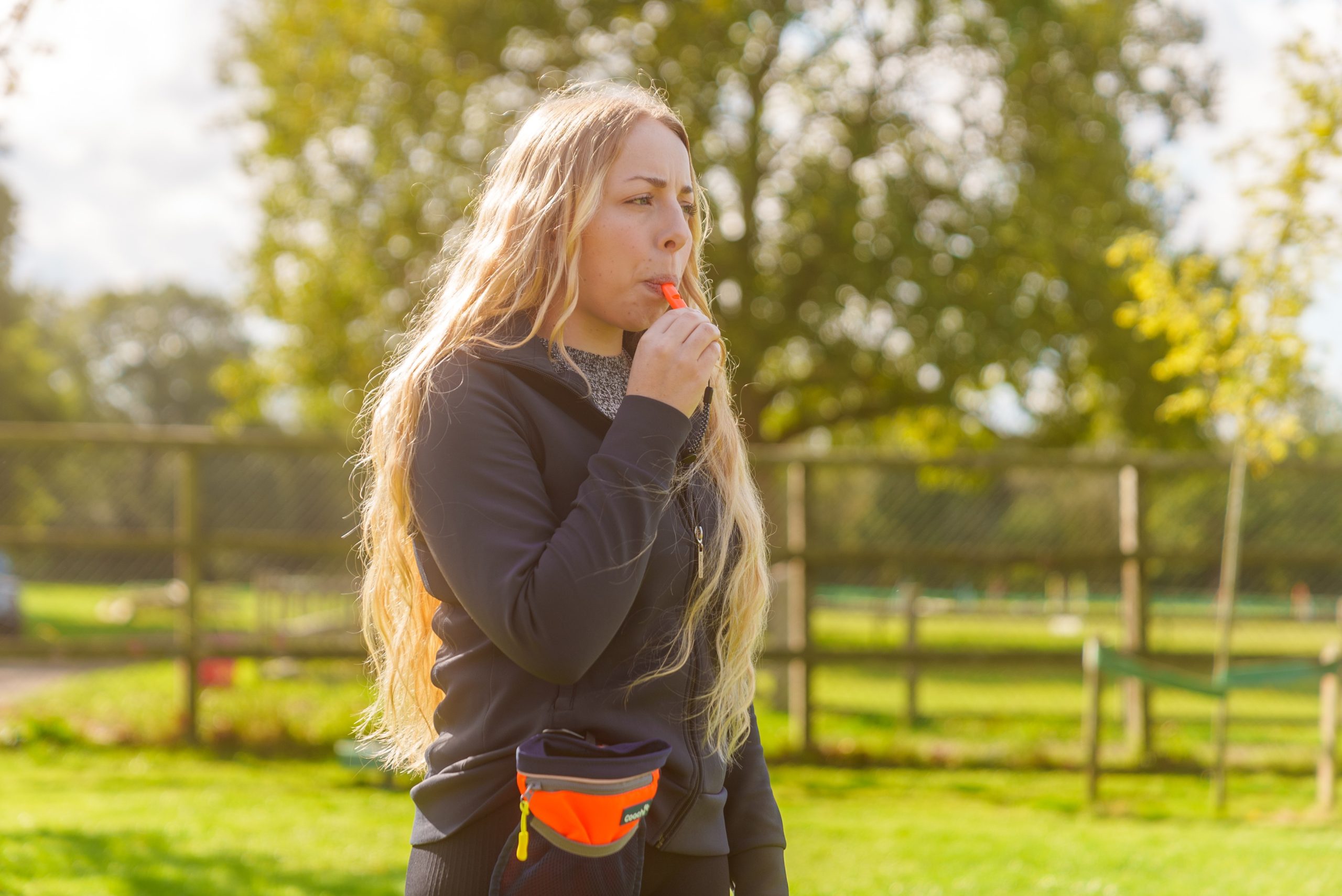 A woman with a Coachi Dog training whistle and Coachi treat pouch